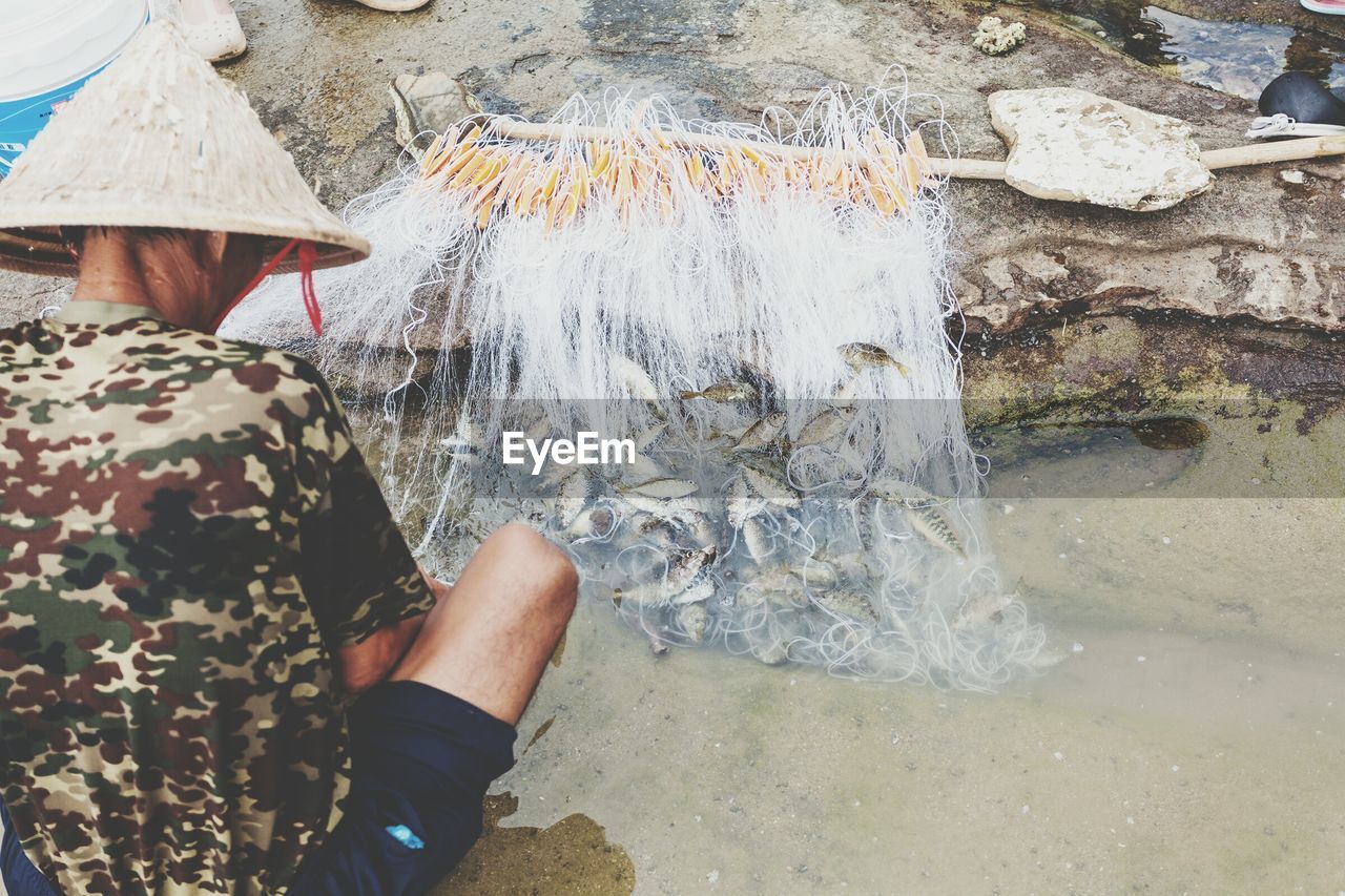 Man looking at fish in net against rock