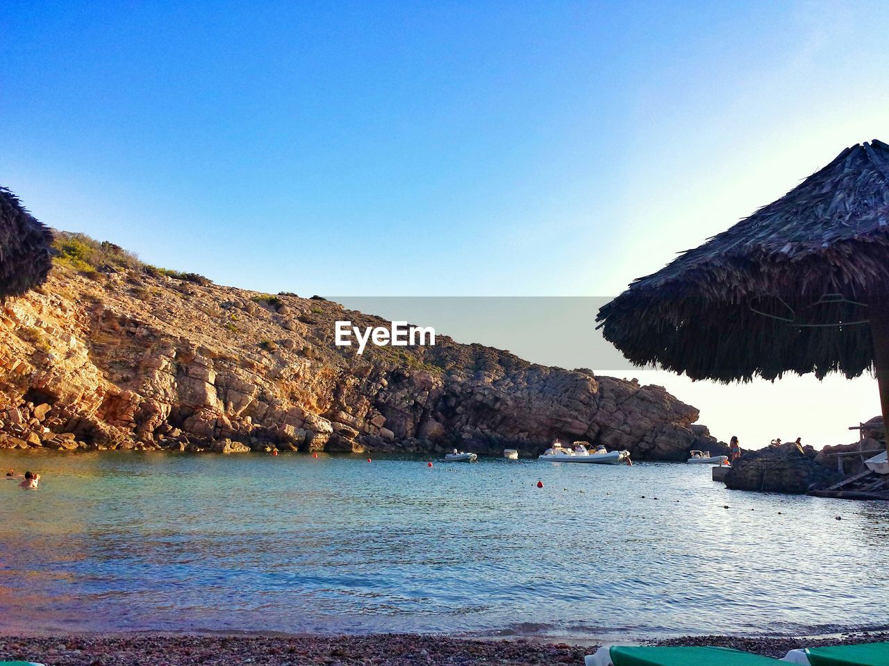 Boats moored on sea by mountain against sky