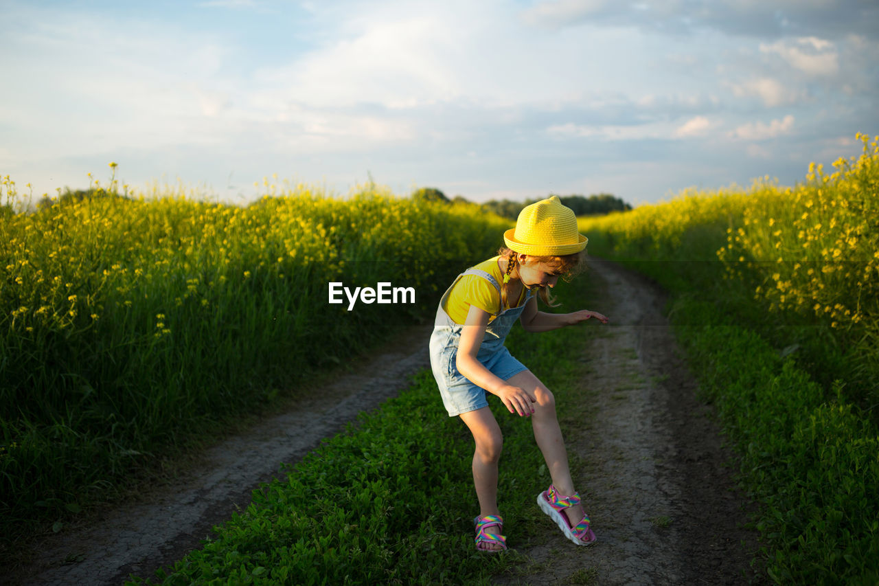 FULL LENGTH OF WOMAN ON FIELD AGAINST YELLOW SKY