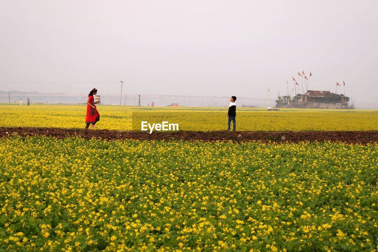 PEOPLE PLAYING ON FIELD AGAINST SKY