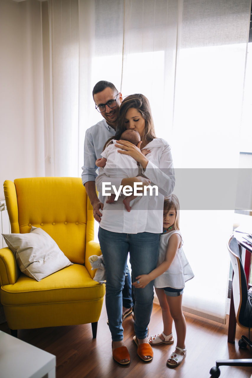 Family of four with newborn baby kissing by mother. mom dad older sister and little brother.