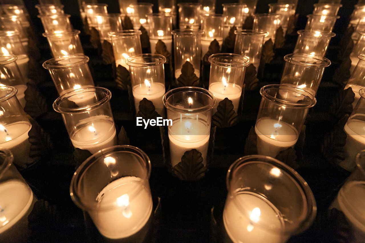 Full frame shot of lit tea light candles arranged in church