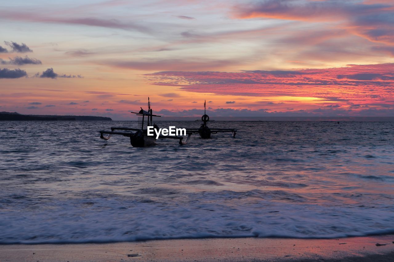 Boat in sea against sky during sunset