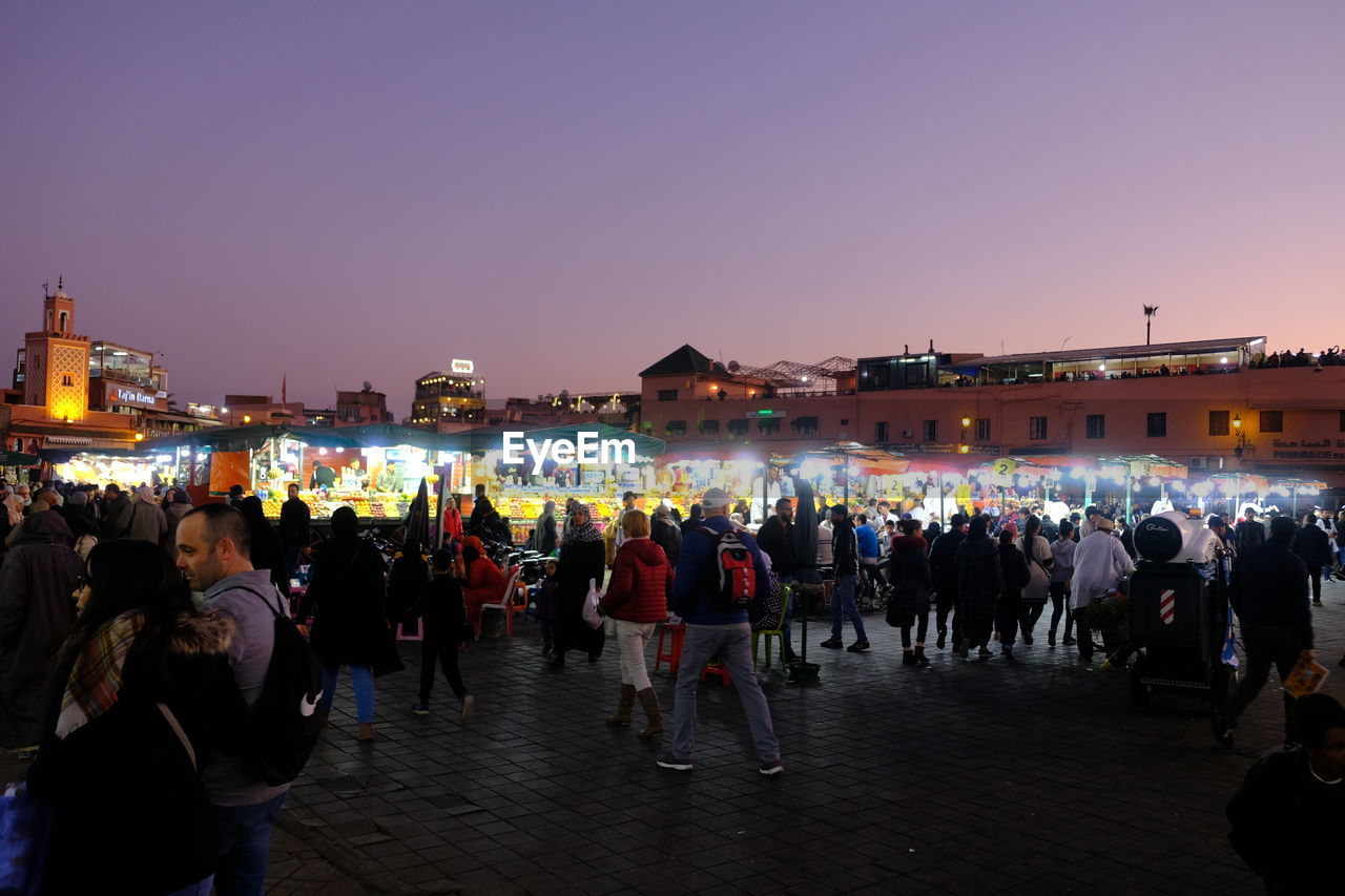 PEOPLE AT ILLUMINATED MARKET AGAINST CLEAR SKY