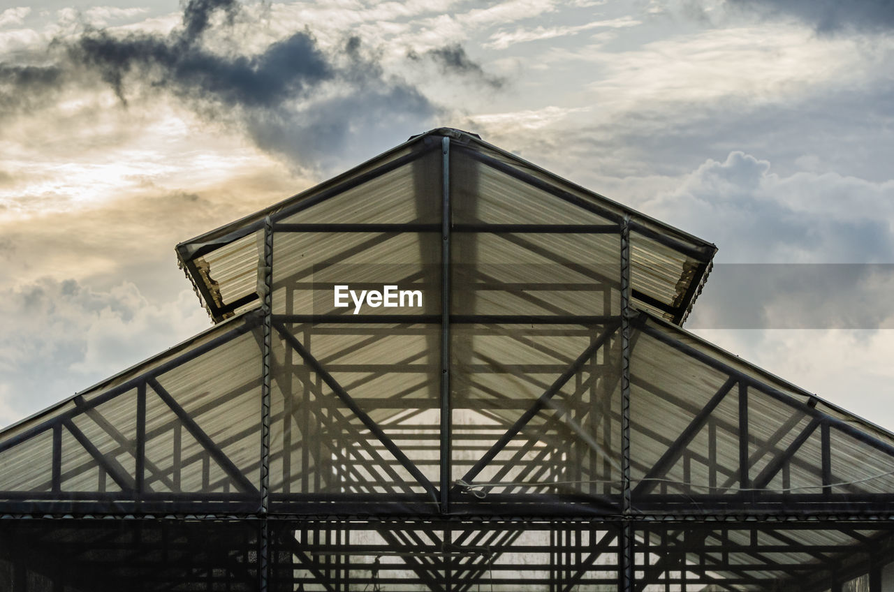 The structure of greenhouse roof is made of steel frames. sky background.