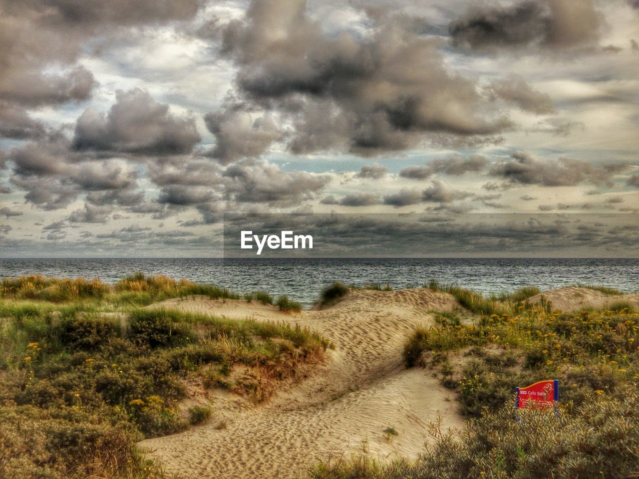 Scenic view of beach against cloudy sky