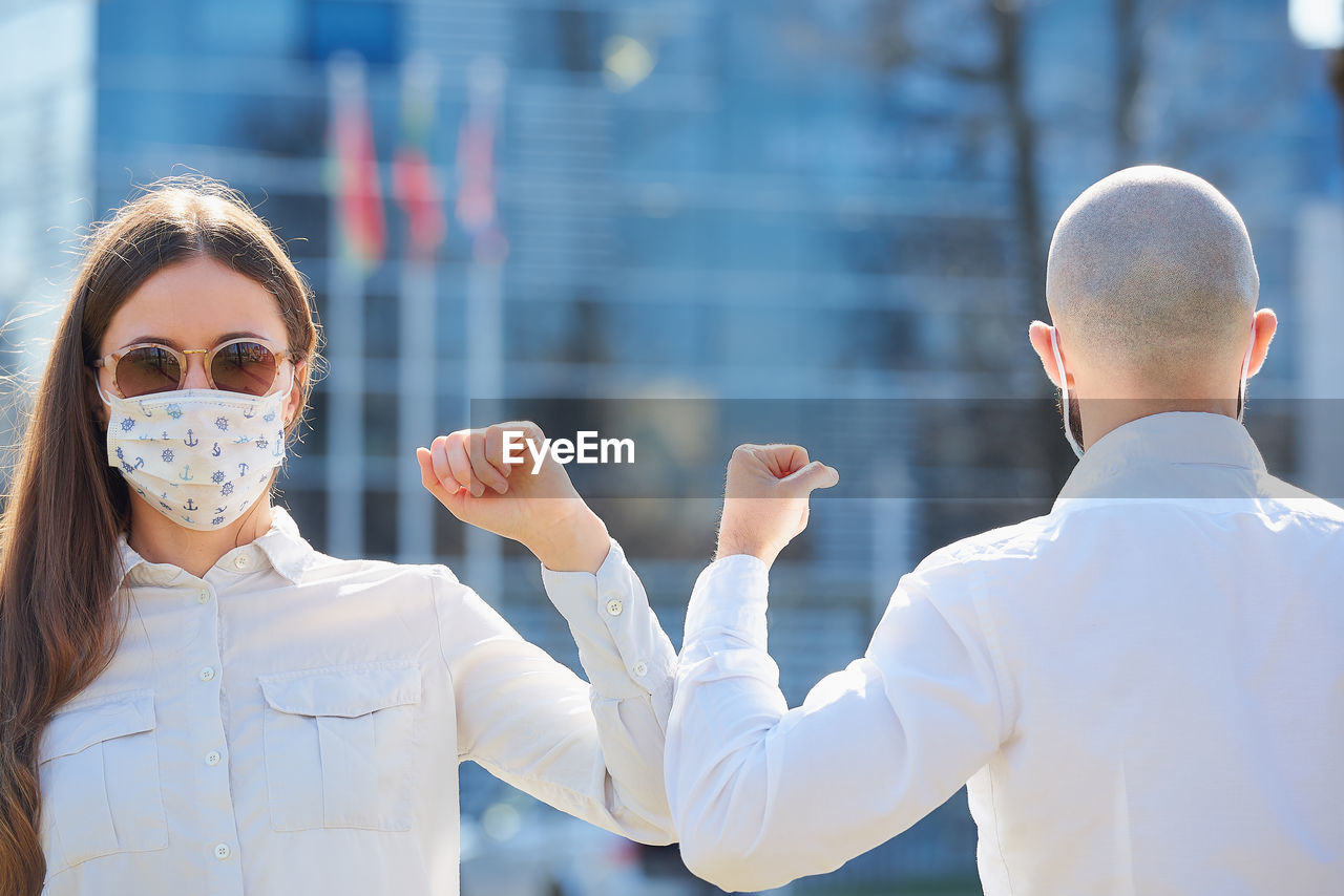 Man and woman wearing mask bumping elbow