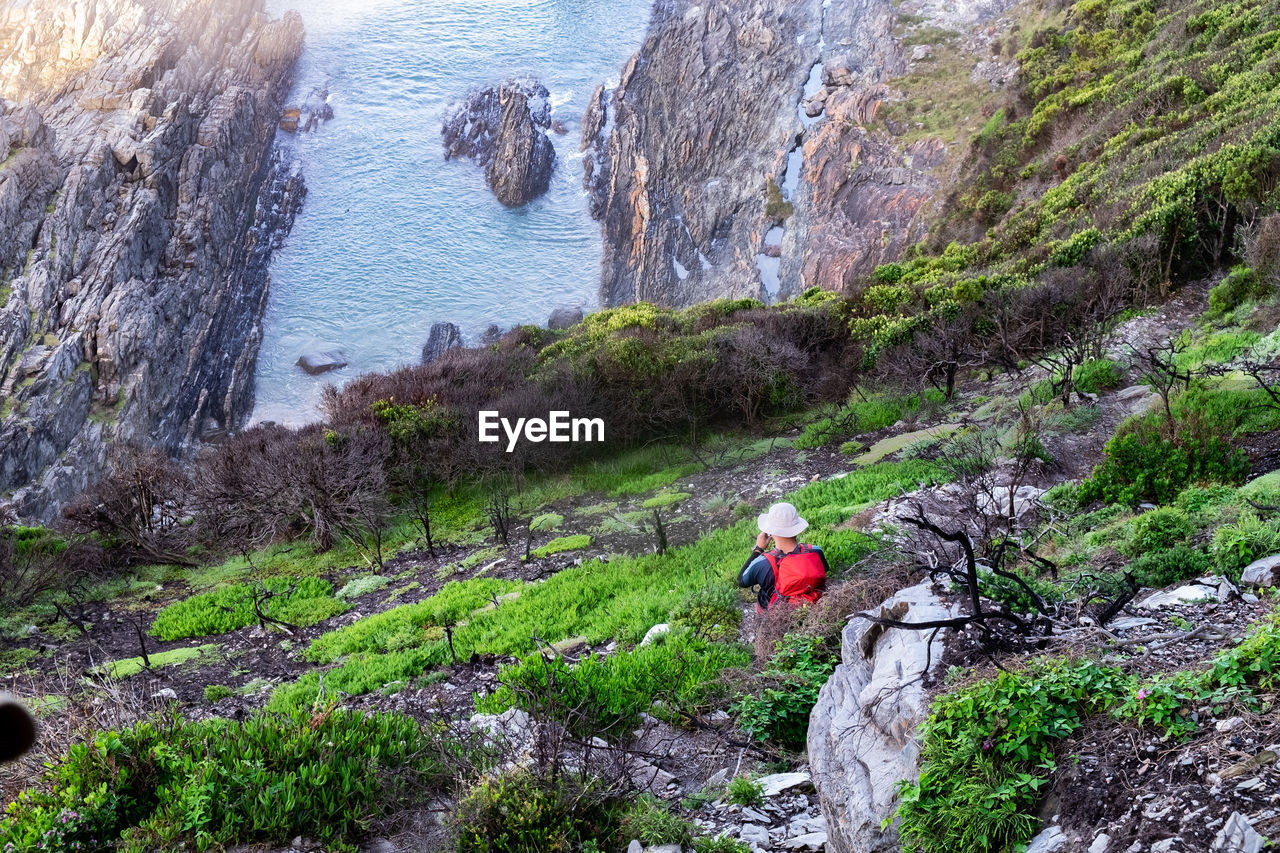 Man with red backpack taking photo of tidal pool