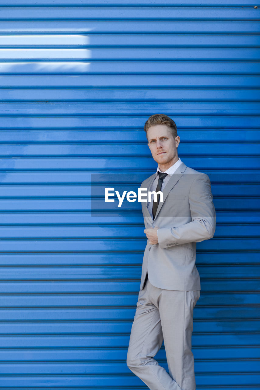 Portrait of businessman standing against closed blue shutter