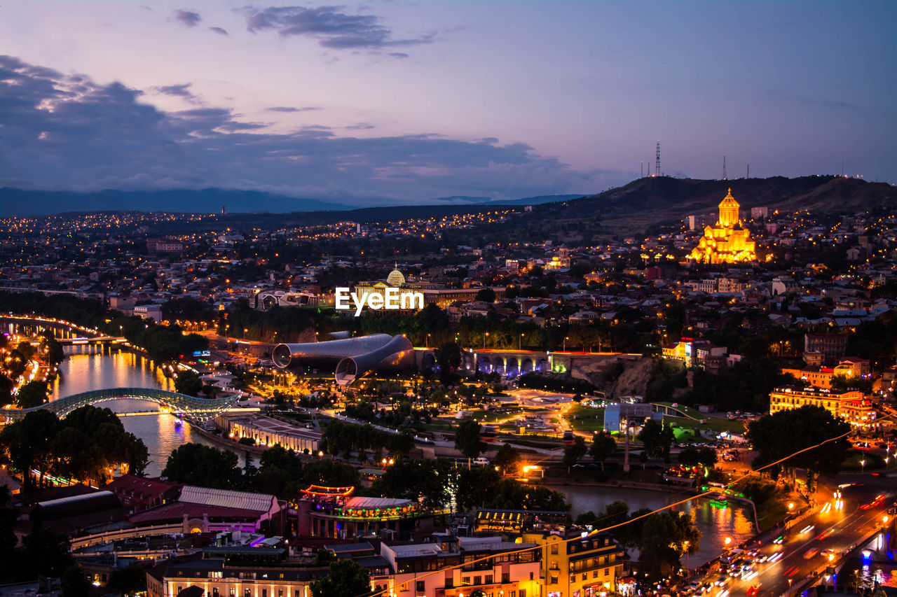 Illuminated cityscape against sky at dusk