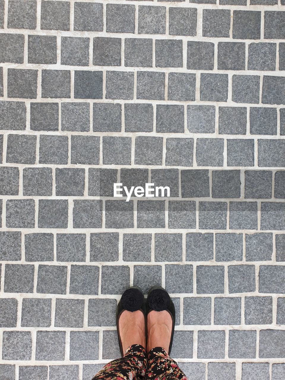 Low section of woman standing on pattern footpath