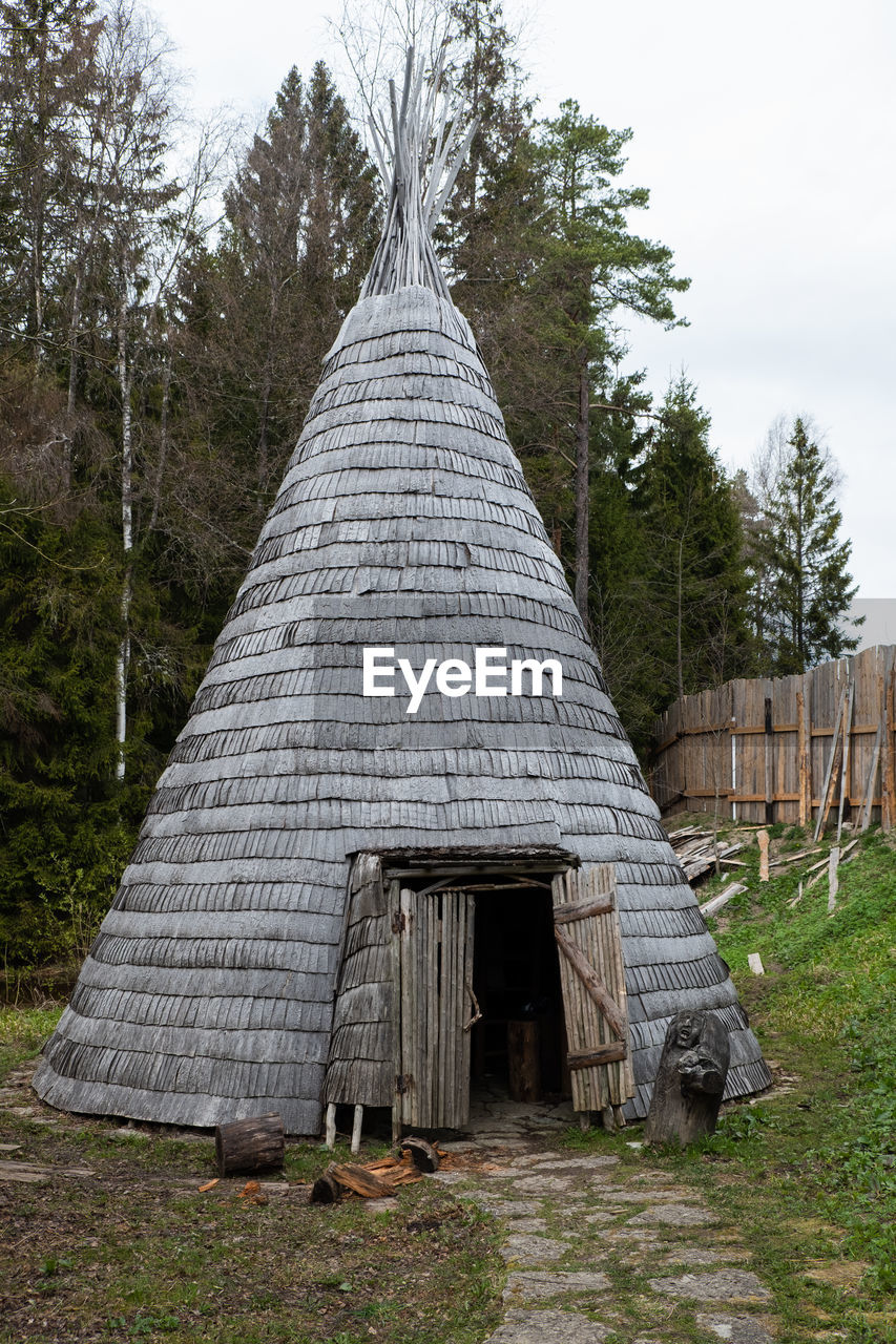 Conical light wooden medieval building with fireplace in the middle.