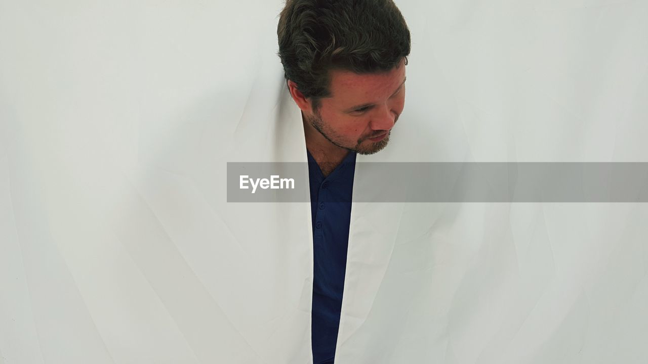 YOUNG MAN LOOKING AWAY AGAINST WALL