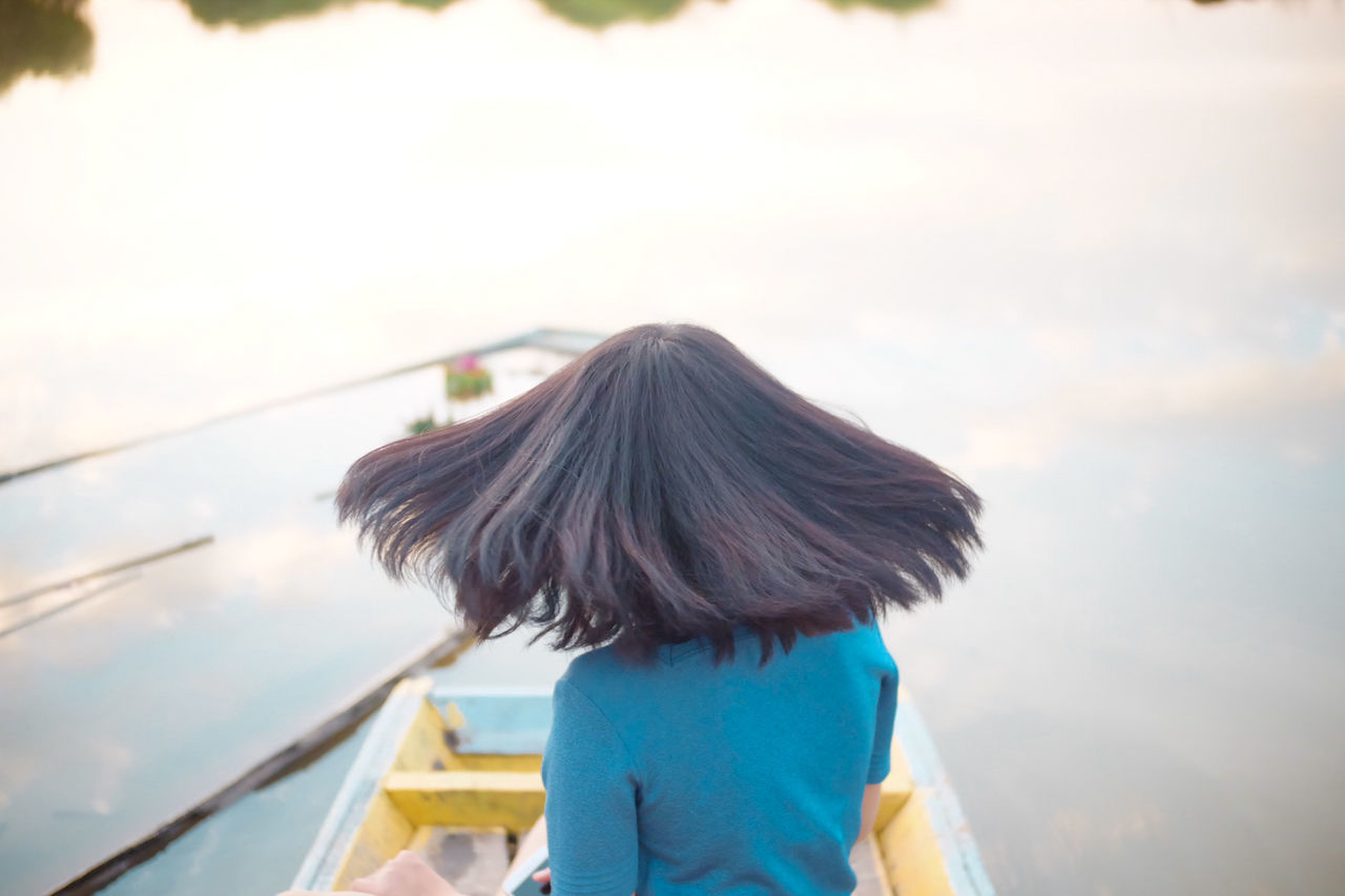 REAR VIEW OF WOMAN LOOKING AT CAMERA