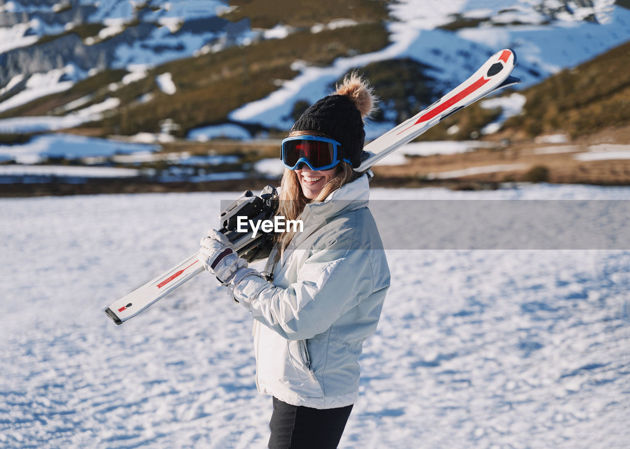 Woman wearing ski goggles while standing on snow covered land