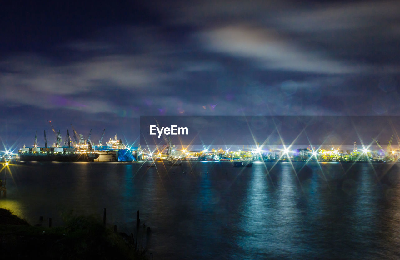 ILLUMINATED BOATS IN SEA AGAINST SKY