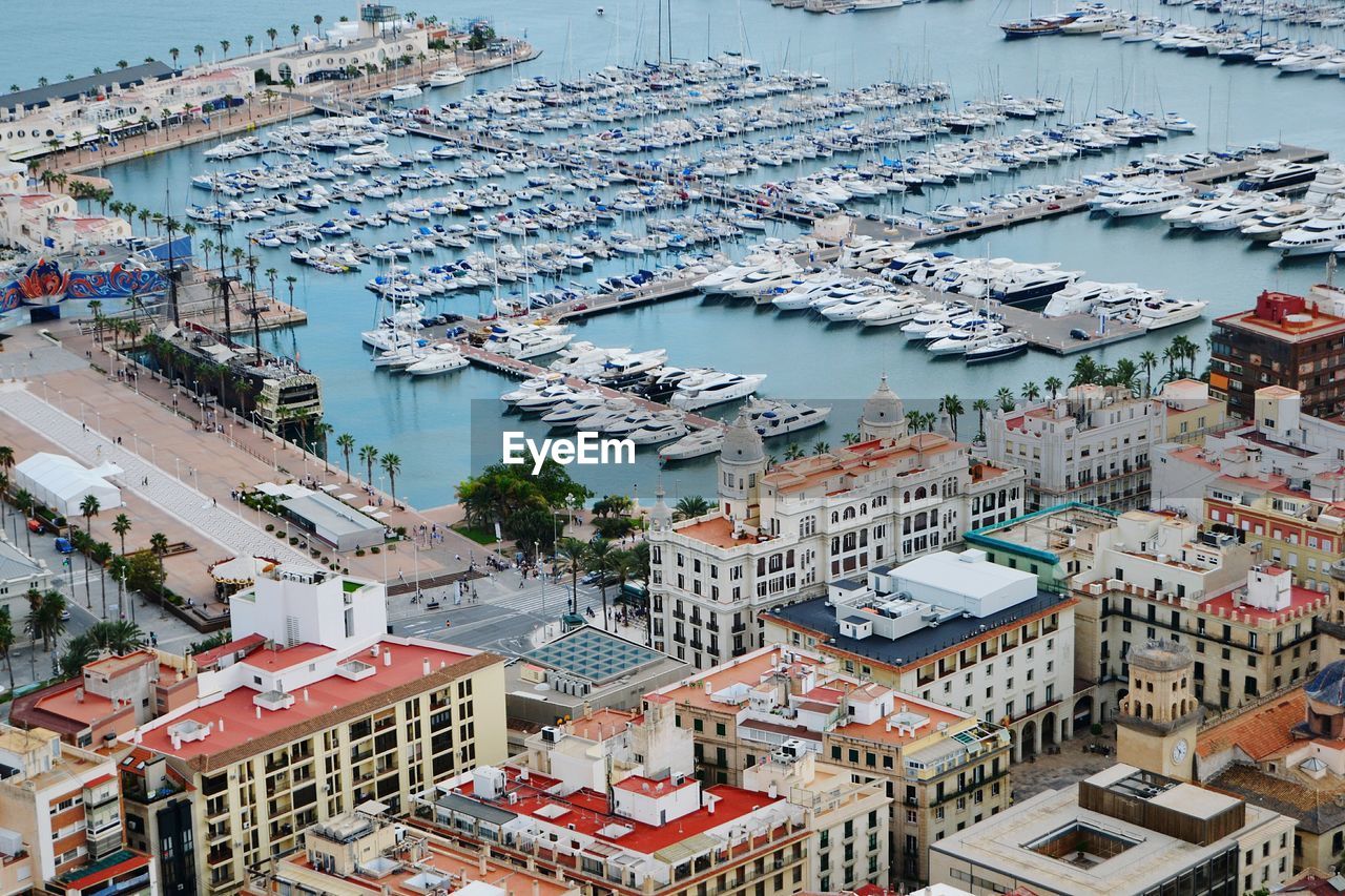 HIGH ANGLE VIEW OF CITY BY MOORED BOATS