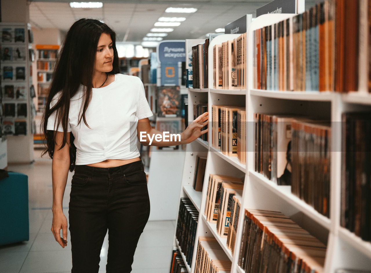 YOUNG WOMAN READING BOOK IN A LIBRARY