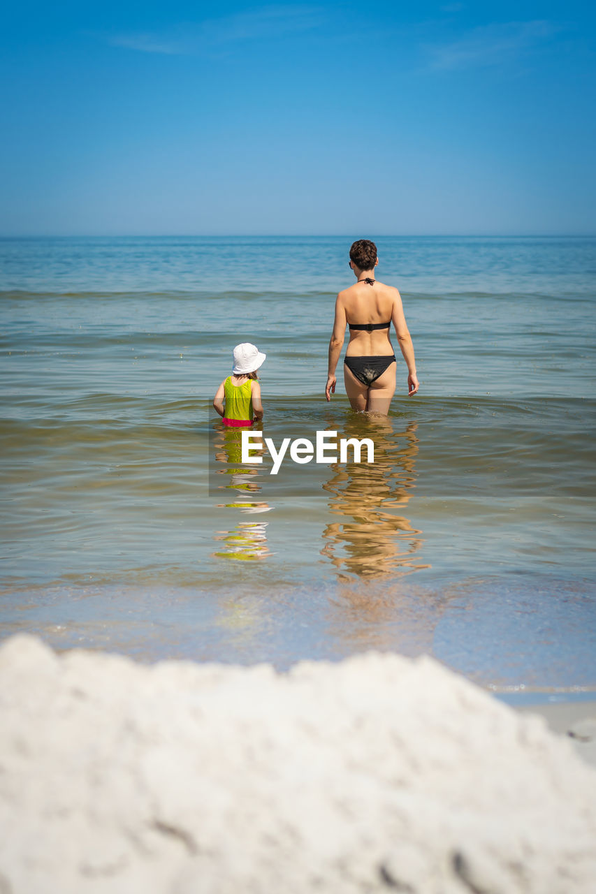 FULL LENGTH OF SHIRTLESS MAN STANDING IN SEA