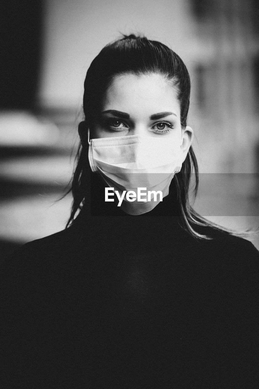 Close-up portrait of young woman wearing chirurgical mask.