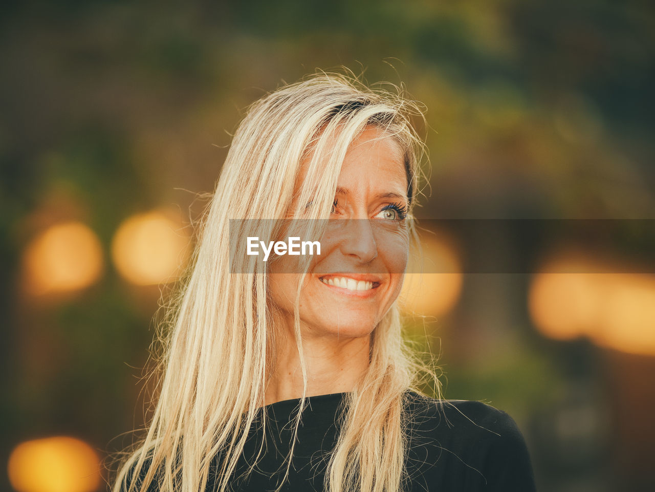 Close-up of smiling woman with blond hair looking away outdoors