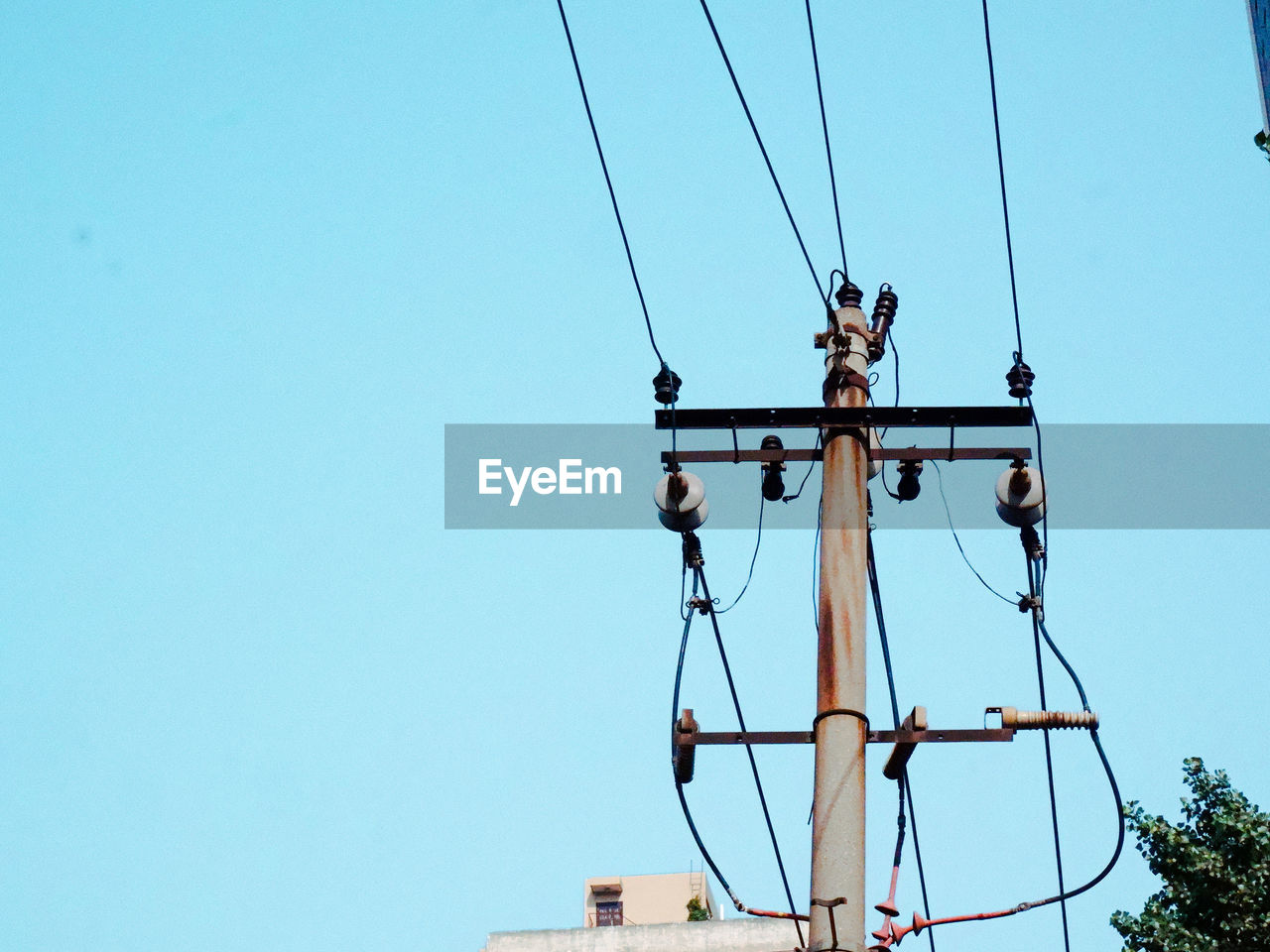 Low angle view of electricity pylon against clear blue sky