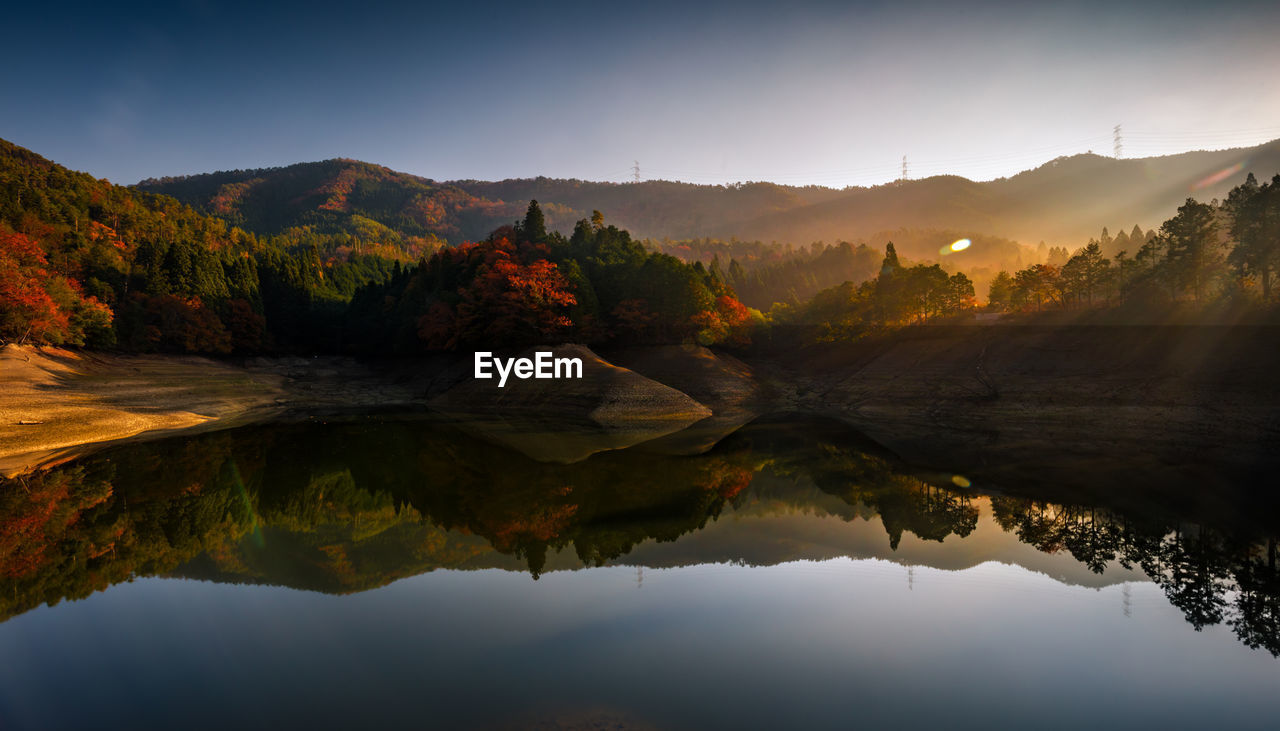 Scenic view of lake by mountains against sky during sunset