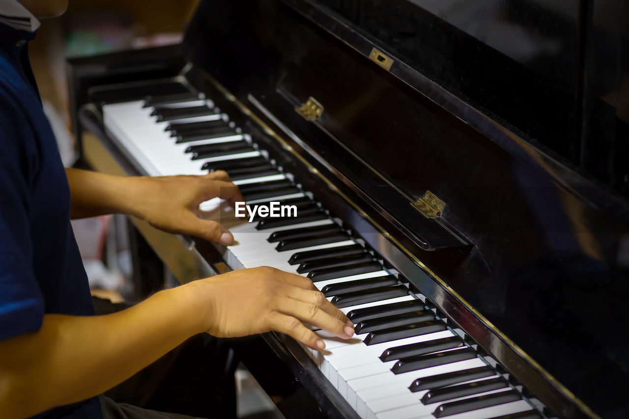 MIDSECTION OF MAN PLAYING PIANO AT MUSIC CONCERT