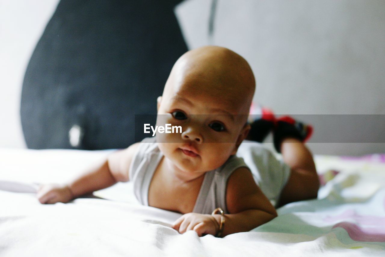 Portrait of cute baby lying on bed at home