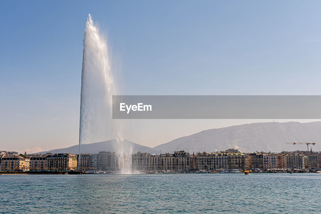 Beautiful view of the water jet fountain in the lake of geneva and the cityscape