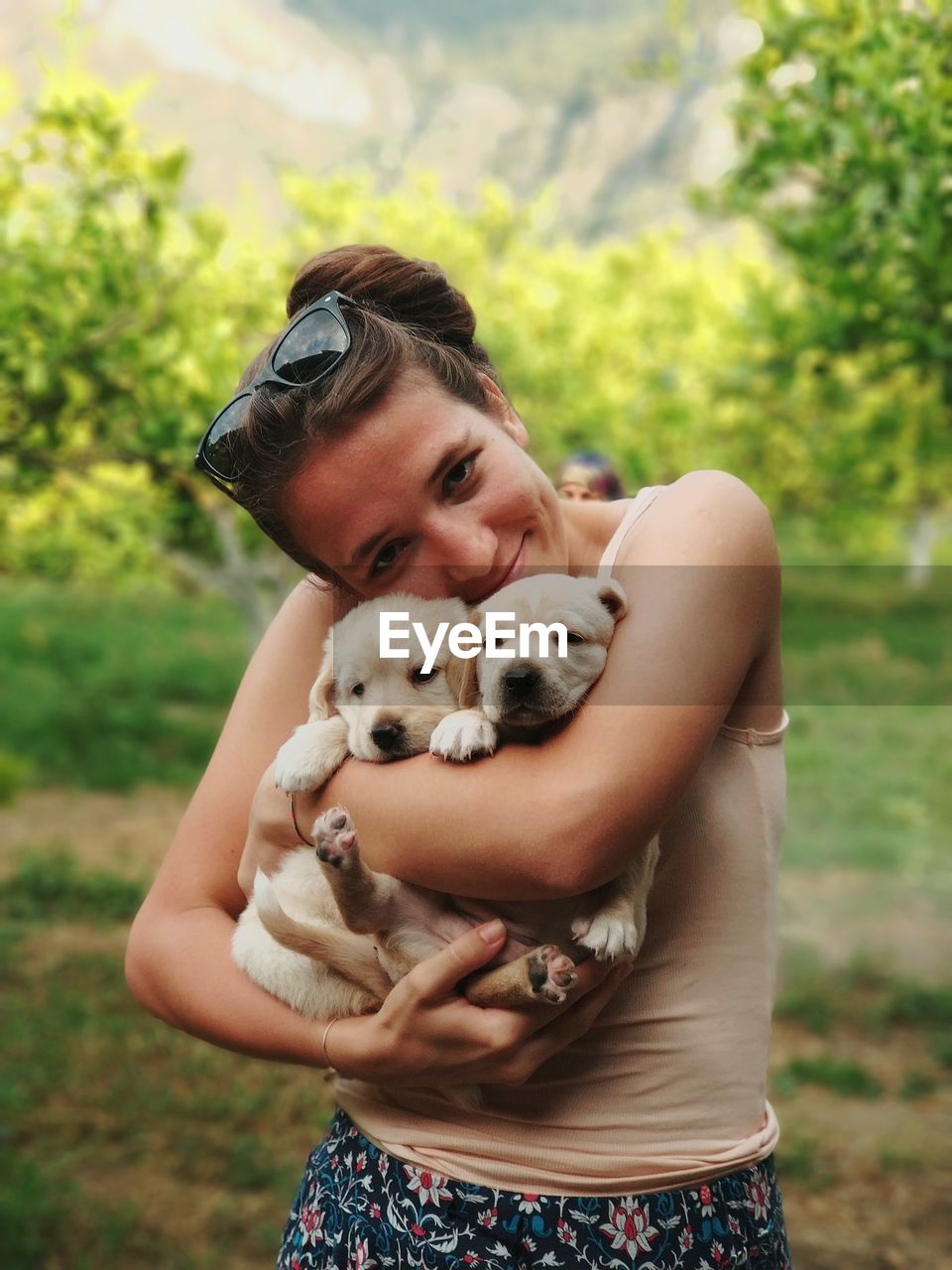 Portrait of woman holding puppies while standing at park