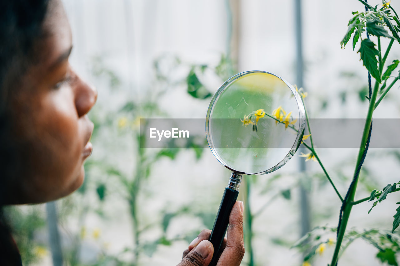 close-up of young man holding magnifying glass