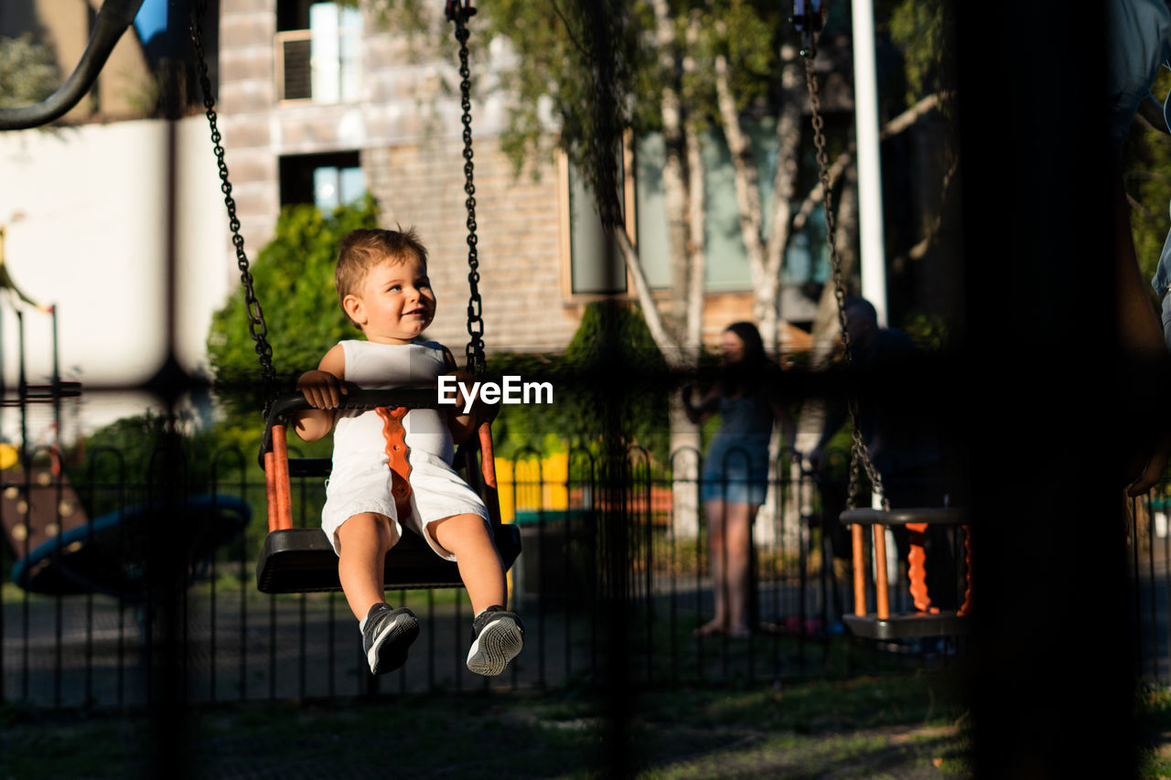 Smiling baby girl swinging in playground