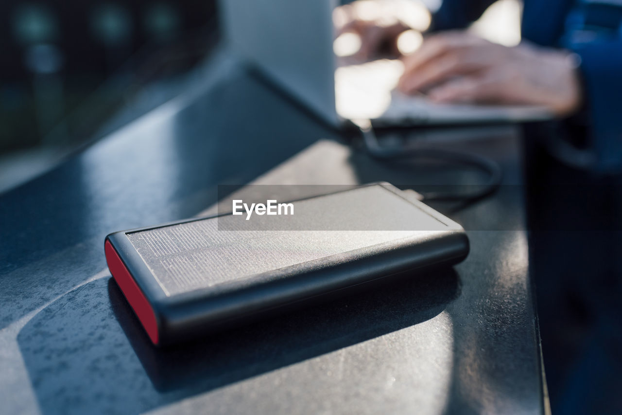 Solar battery charger connected to laptop being used by businessman