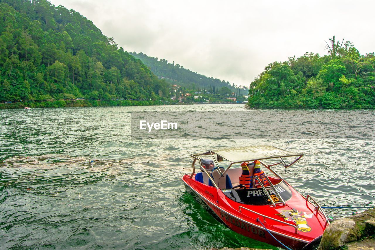 BOATS SAILING IN RIVER AGAINST SKY