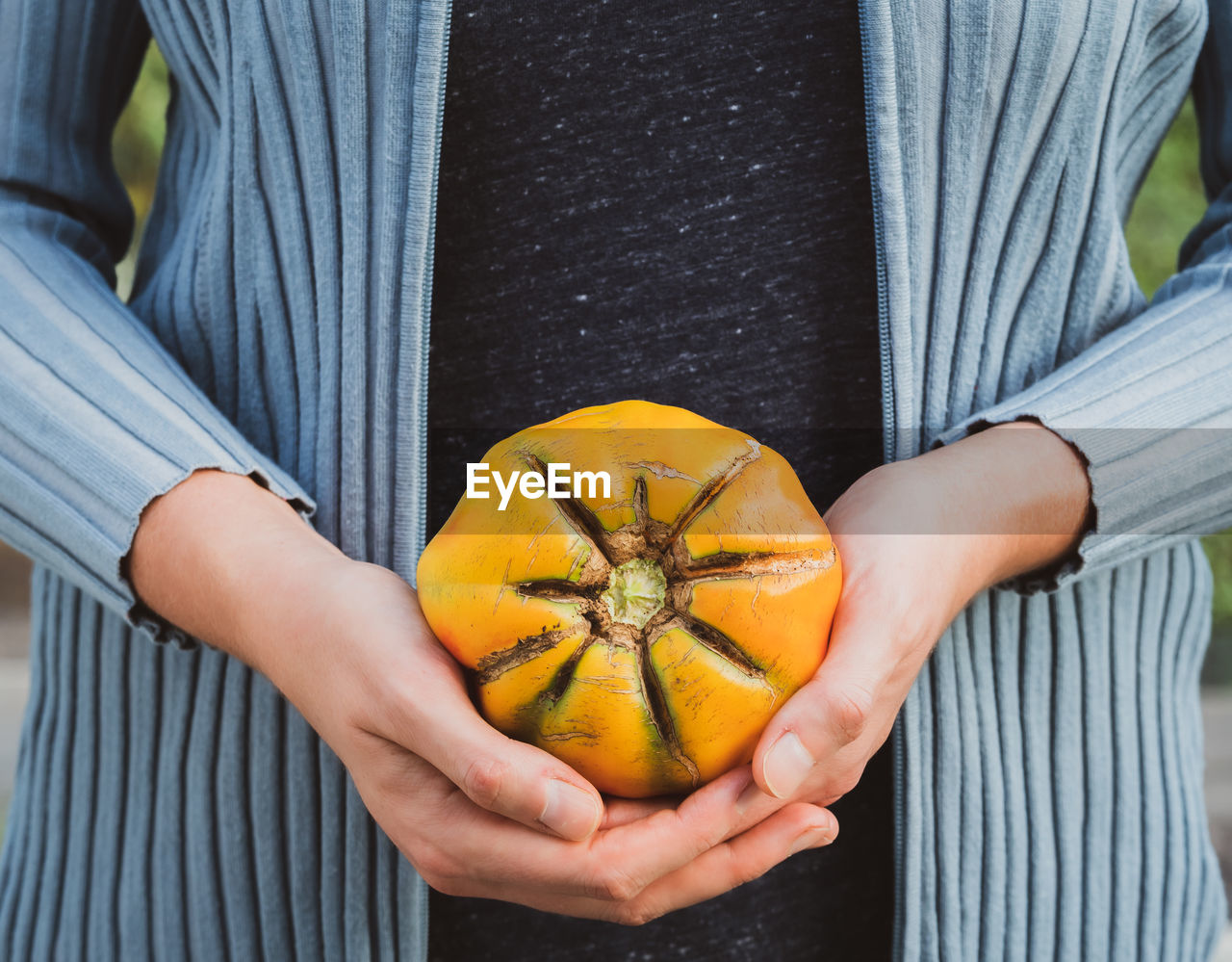 CLOSE-UP OF HAND HOLDING ORANGE