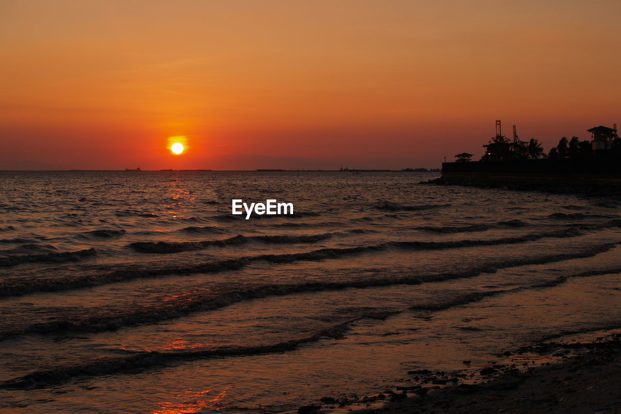 Scenic view of sea against orange sky