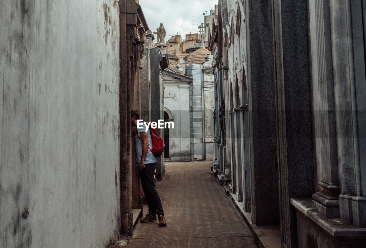 Man standing in alley amidst wall