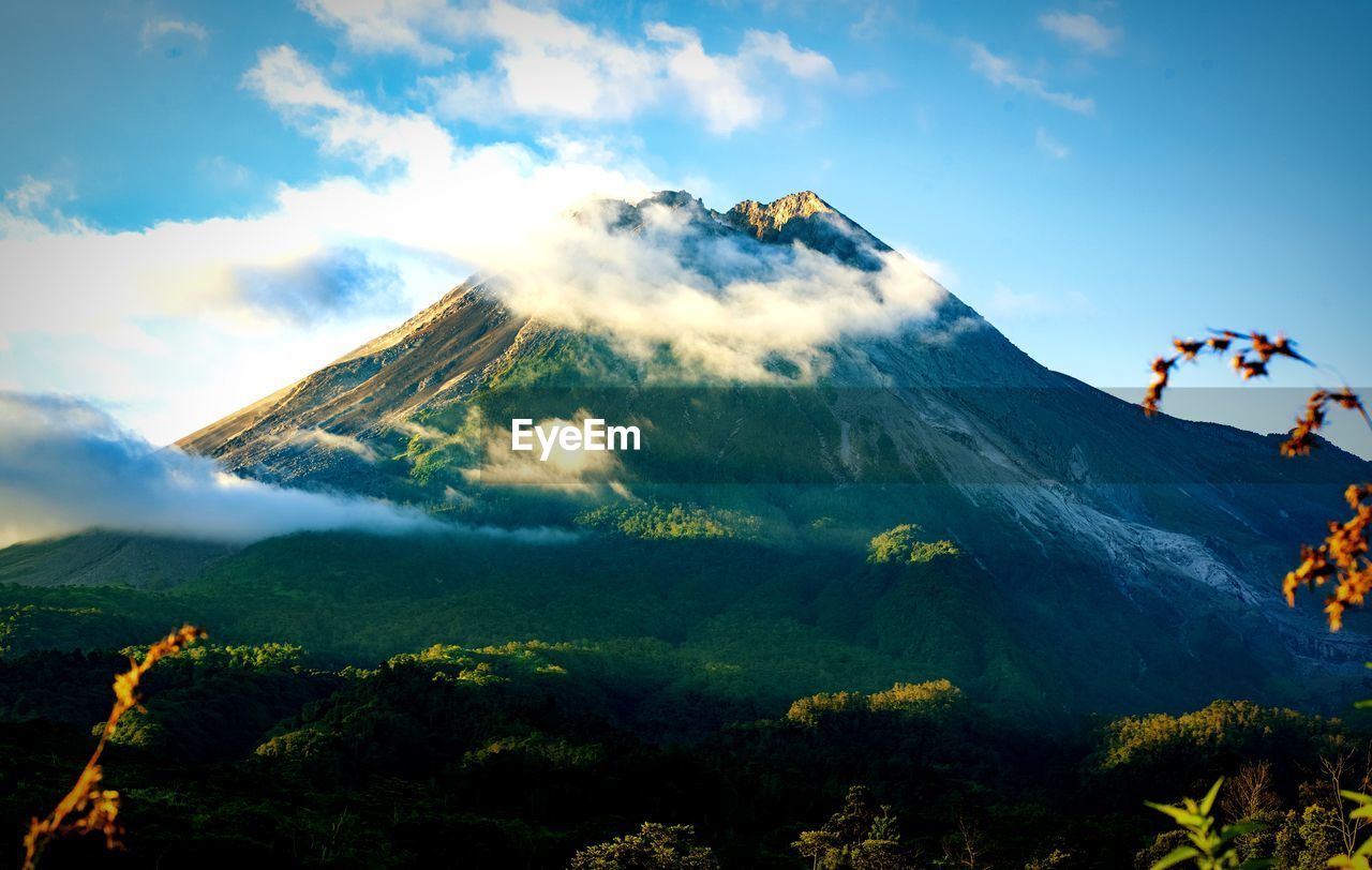 mountain, sky, nature, environment, landscape, beauty in nature, mountain range, scenics - nature, cloud, land, mountain peak, travel, adventure, plant, tree, activity, outdoors, sports, travel destinations, leisure activity, forest, day, non-urban scene, motion, volcano, extreme sports, sunlight, vacation, blue