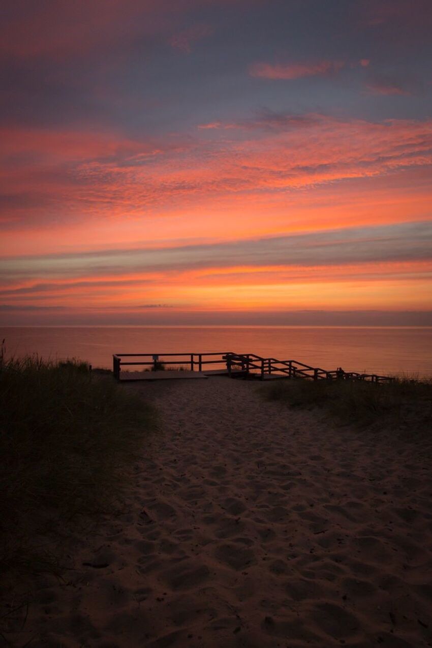 Scenic view of beach by sea against sky during sunset