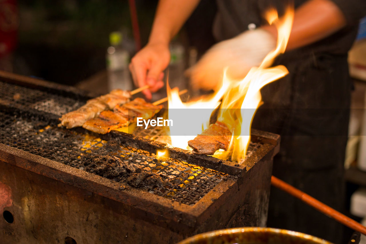 Midsection of man preparing food on barbecue grill