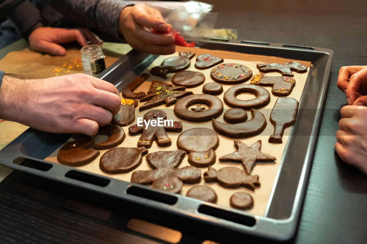 A group of friends prepares ginger cookies of different shapes before christmas