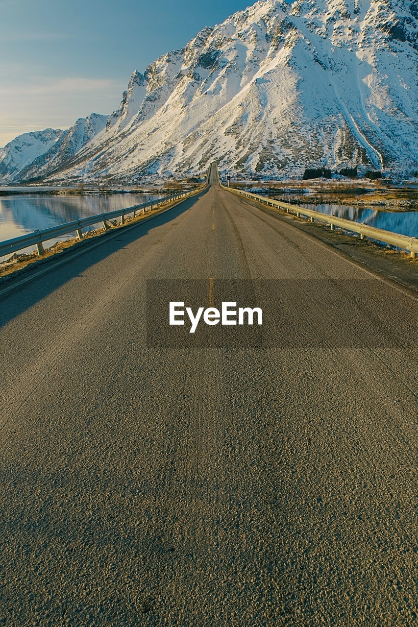 Empty road leading towards snow covered mountain