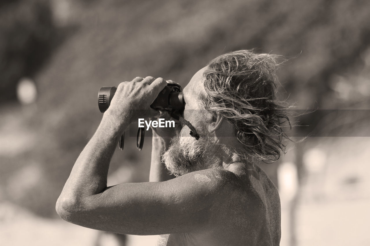 Side view of senior man looking through binoculars