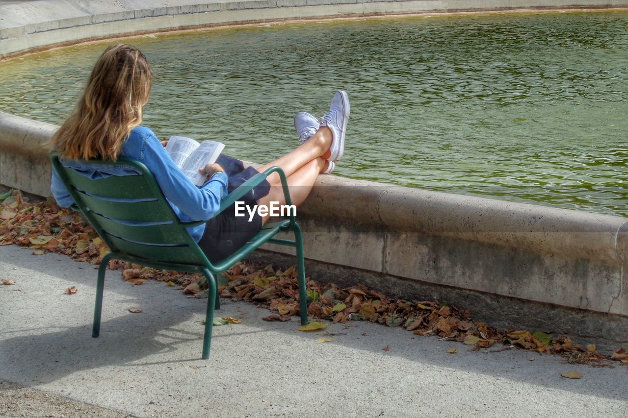 WOMAN SITTING ON CHAIR AT SEA