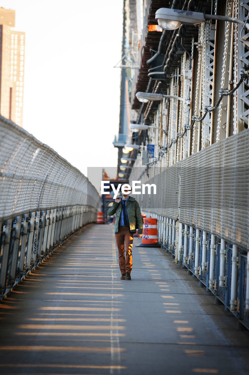 Man looking away while walking on pedestrian walkway of manhattan bridge