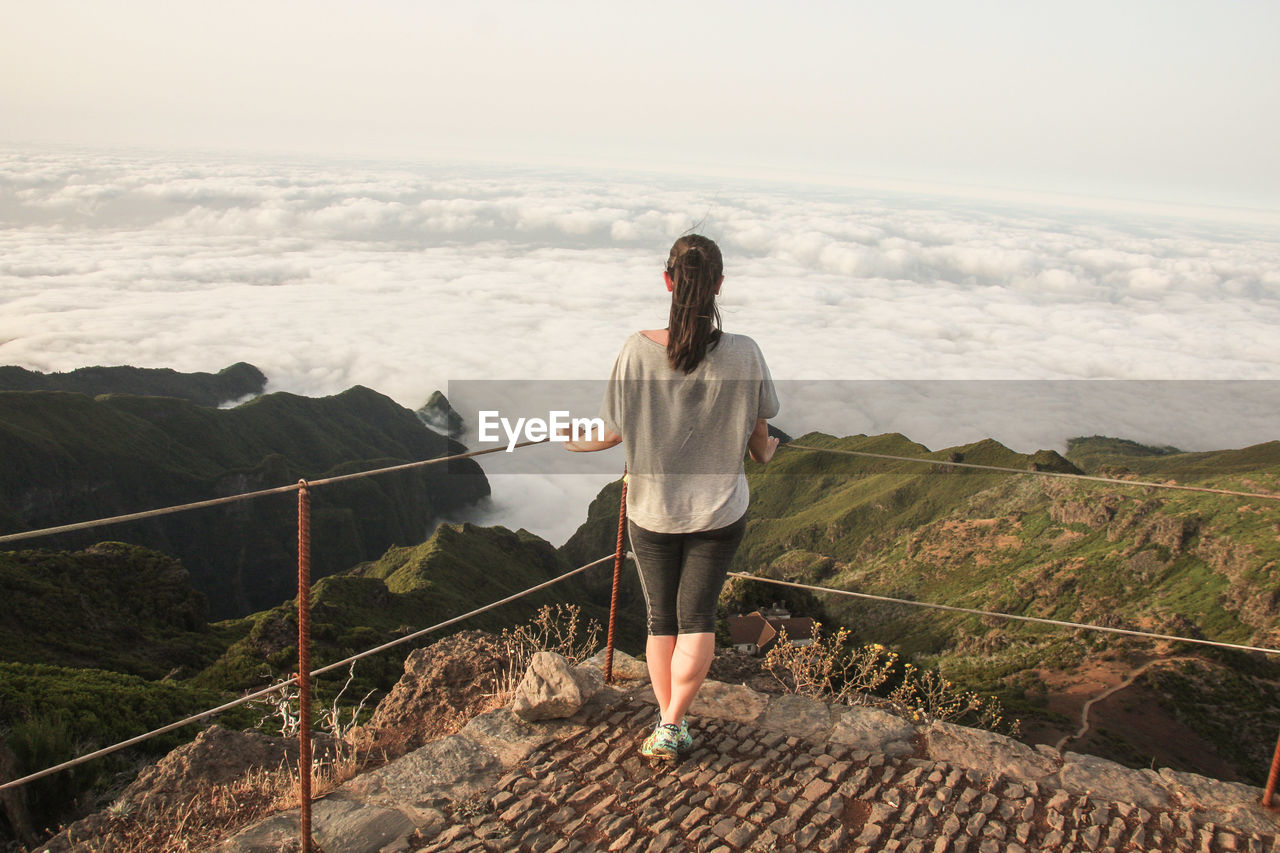 Full length rear view of woman looking at sea by railing