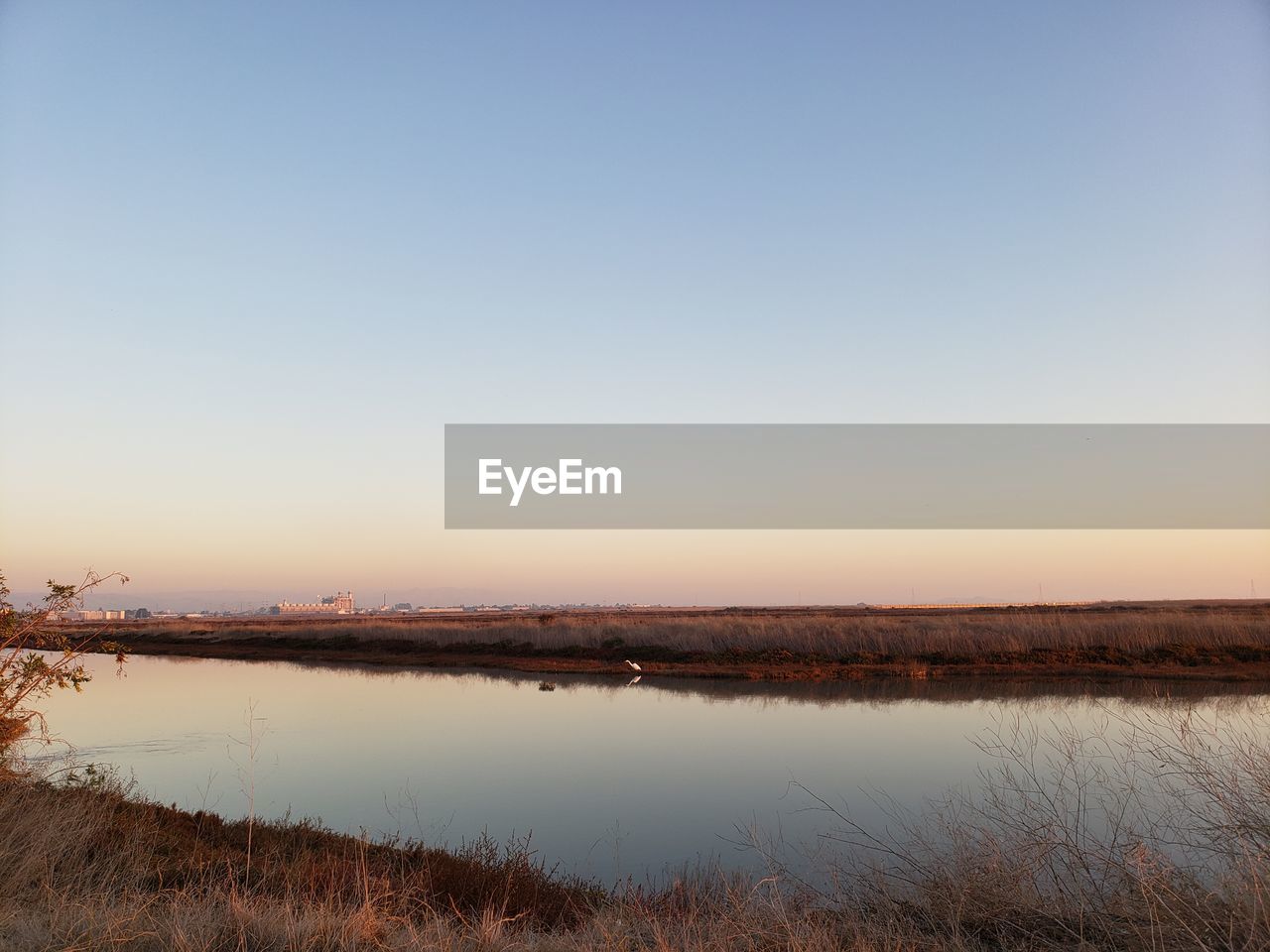 Scenic view of lake against clear sky during sunset