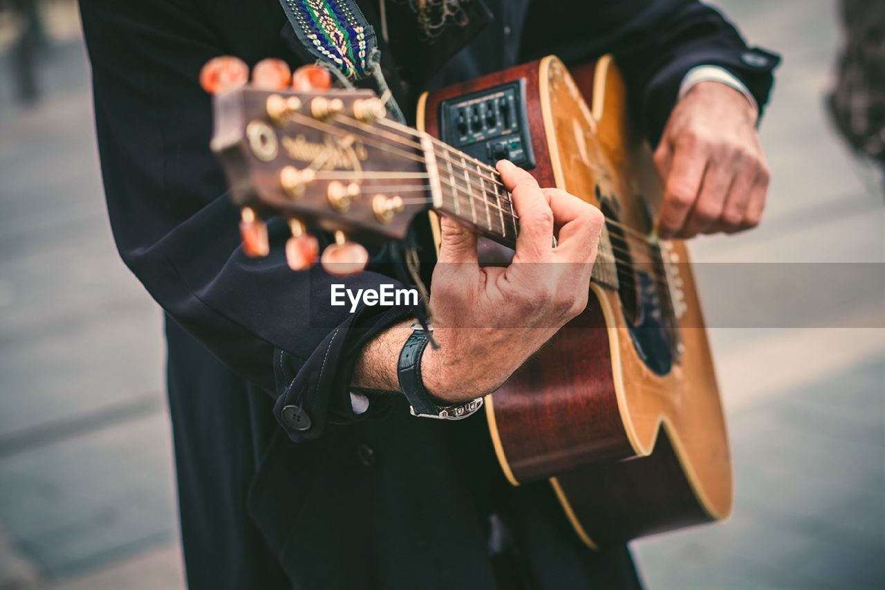 Midsection of man playing guitar