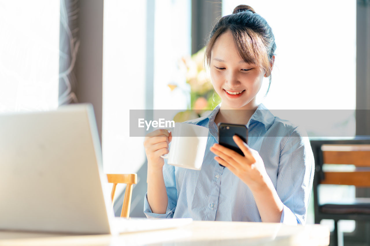 businesswoman using laptop while sitting on table at home